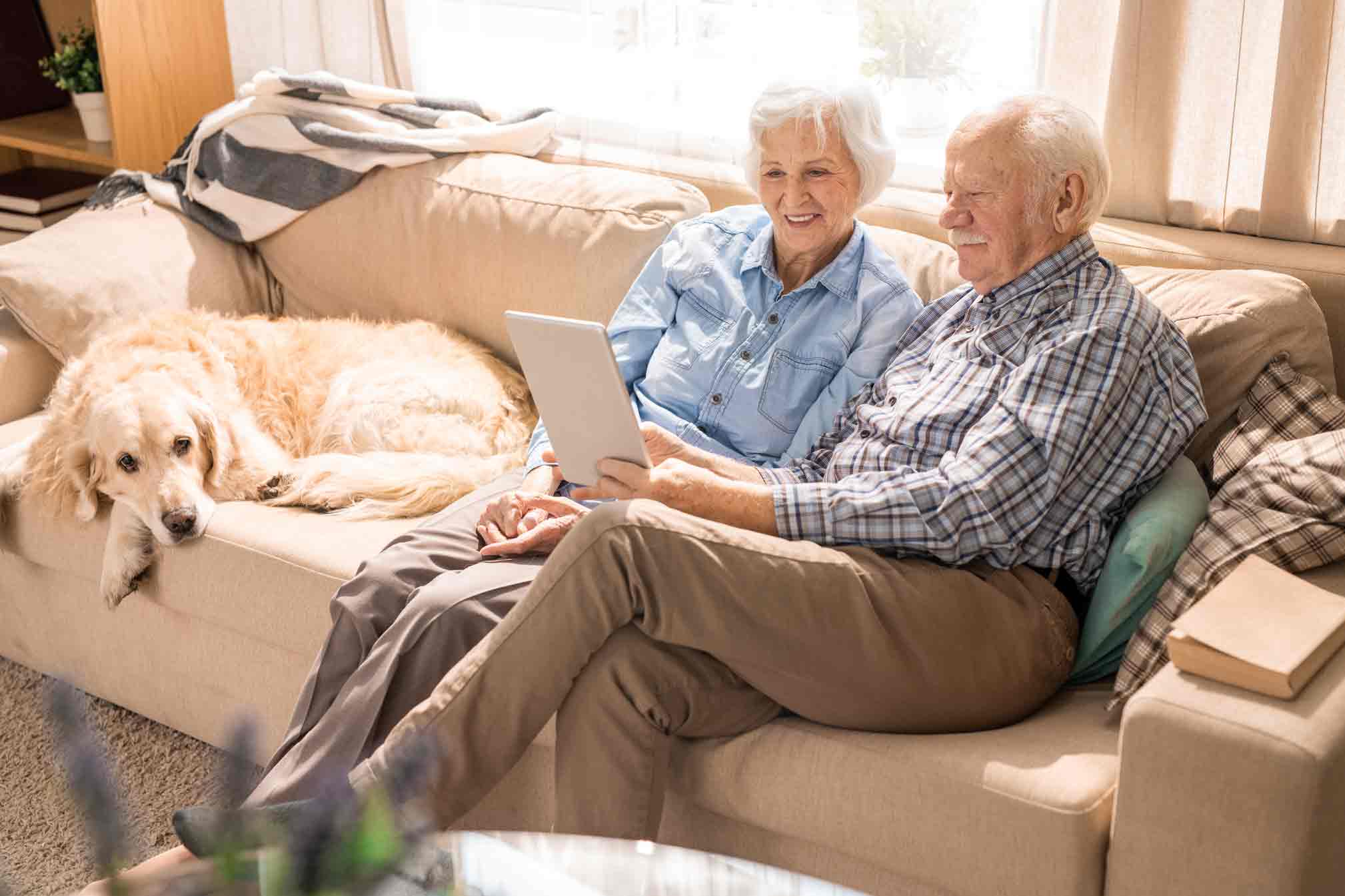 Elderly couple sitting on couch with their dog.